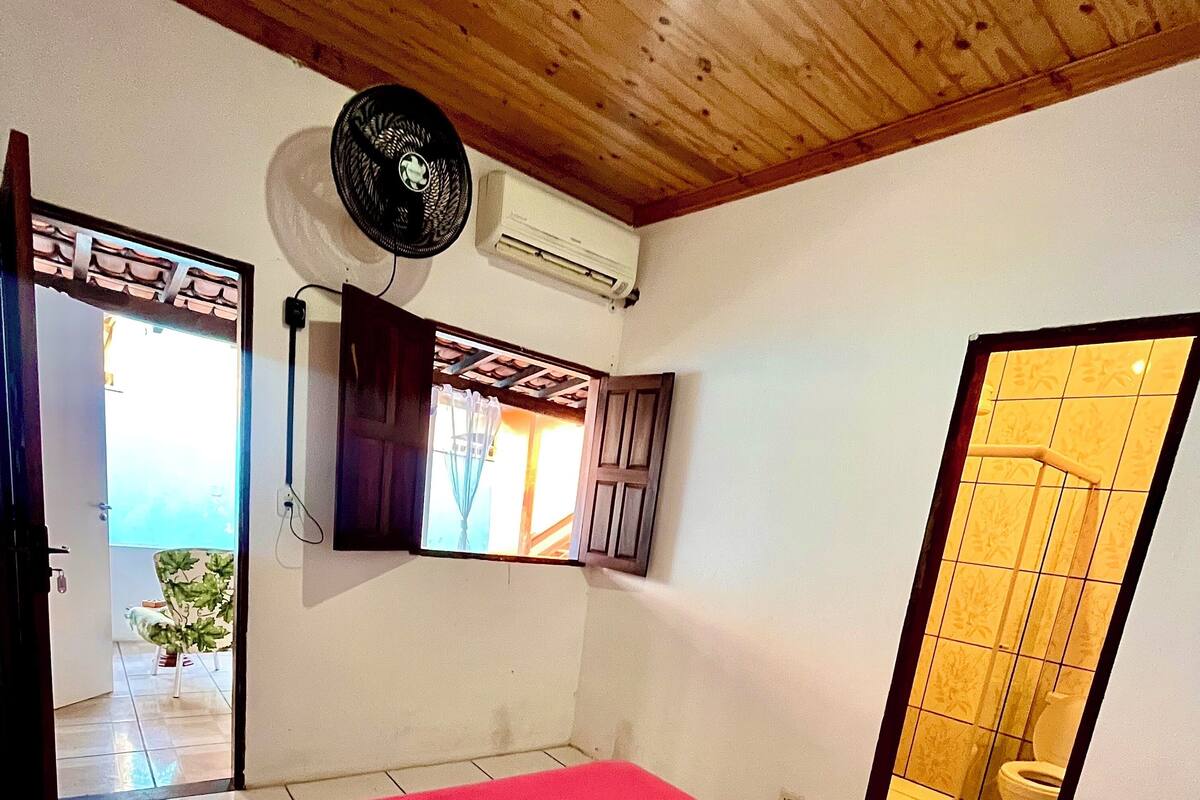 Une chambre avec un lit, une fenêtre, un appareil de climatisation et une vue sur une salle de bain.