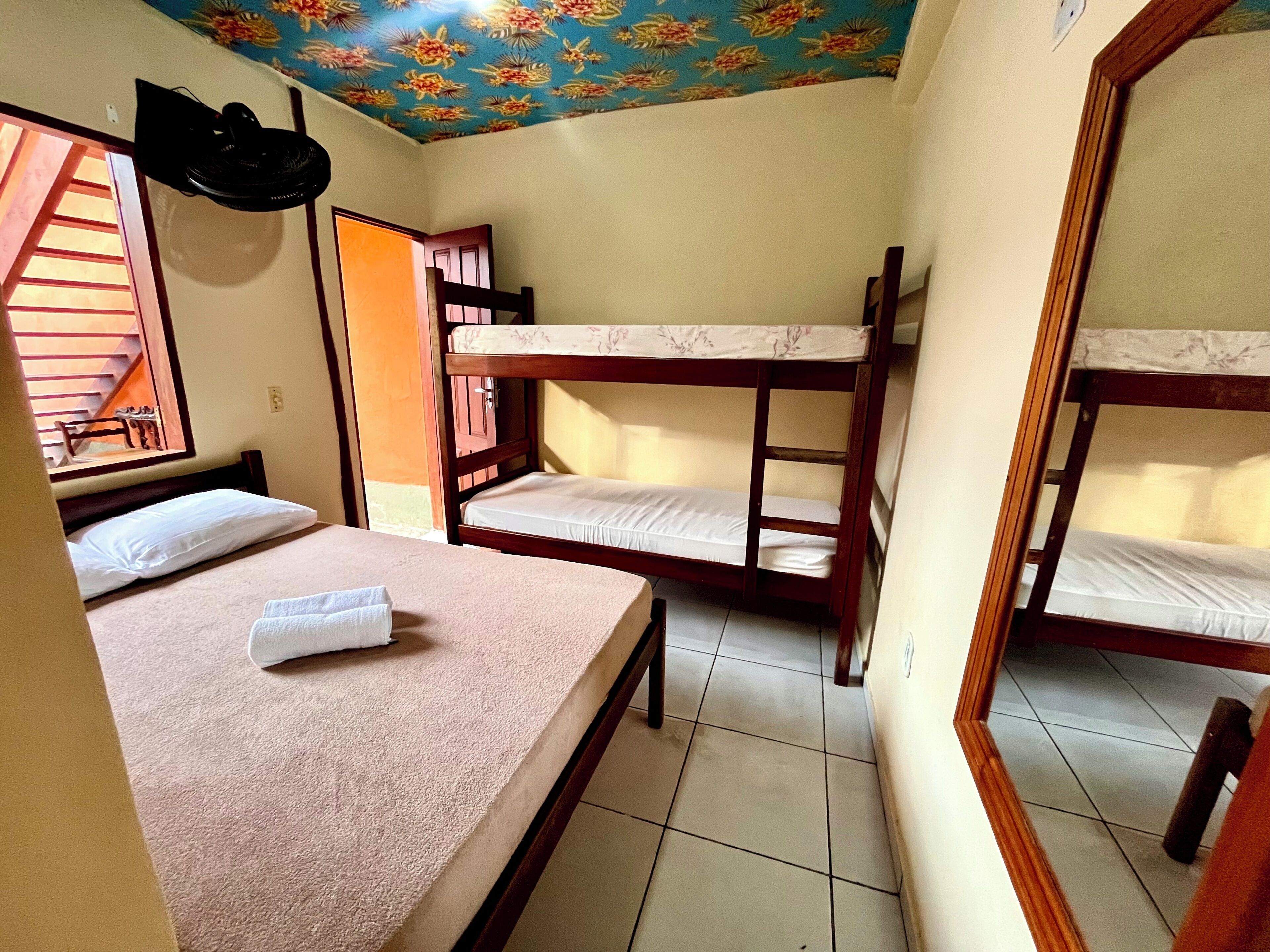 Una habitación con literas, una mesita pequeña y una ventana que da a una escalera.