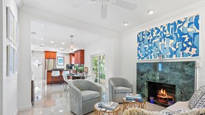 A modern living room with a fireplace, a dining area, and a kitchen.