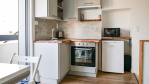 Une cuisine compacte équipée d’un four encastré, d’un four à micro-ondes et d’un lave-vaisselle.