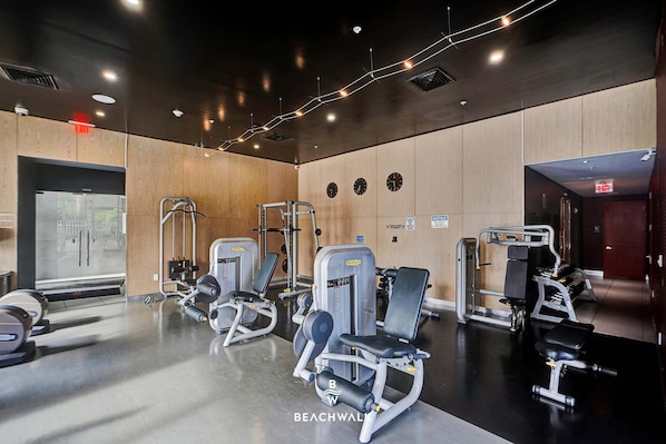 A gym with exercise equipment, wooden walls, and a mirrored wall.