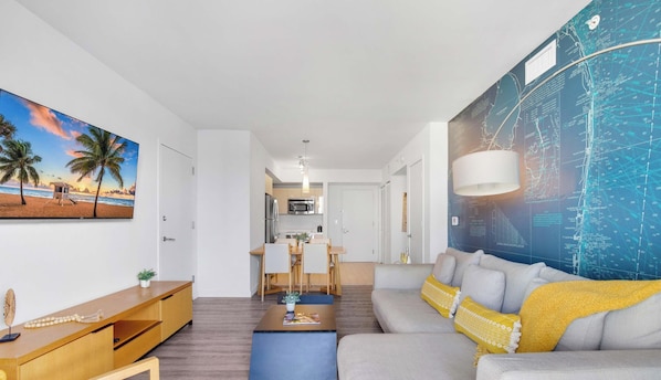 A modern living room with a sofa, coffee table, and a painting of a beach scene.