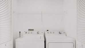 A laundry room with two front-loading washing machines and a dryer.