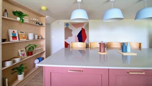 Una cocina moderna con una isla central, estantes de madera e iluminación colgante.