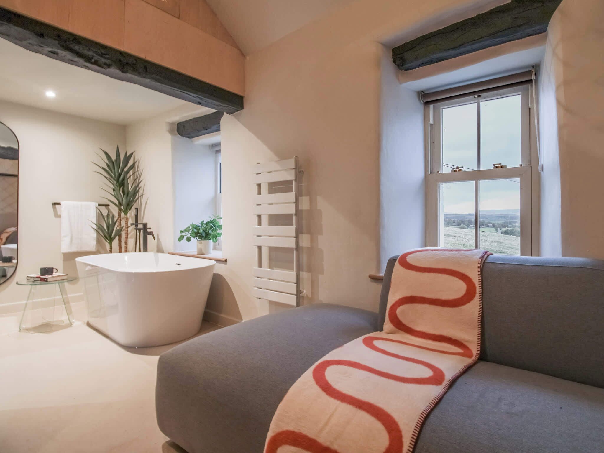 A modern bathroom with a freestanding bathtub, a towel rack, and a potted plant.