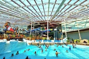 An indoor water park with a large pool, slides, and a covered area. - 5BR, Speakeasy, Fire Pit, Pool Table, HotTtub (Pocono Lake)