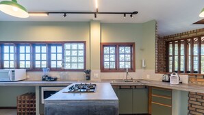 A modern kitchen with a central island, large windows, and a brick accent wall. - House With BBQ 550m From the Beach Gss0488 (Florianópolis)