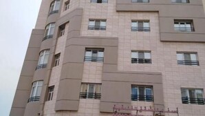 Un immeuble à plusieurs étages sur lequel on peut lire l’inscription « Appartements d’hôtel ».