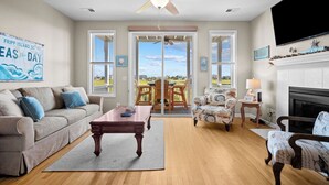 Un salón amplio con ventilador de techo, chimenea y un ventanal con vistas panorámicas.