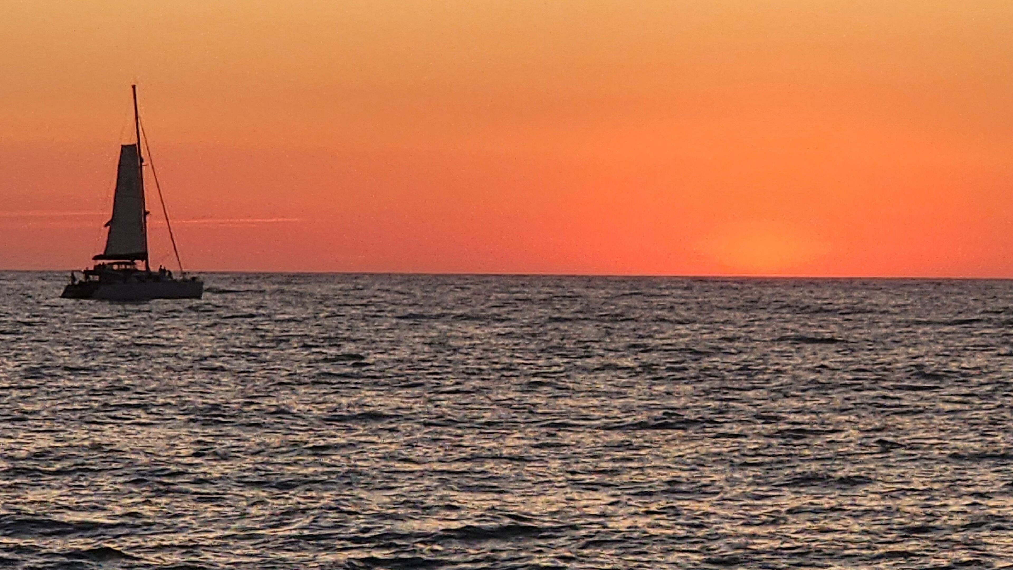 A sailboat on calm waters during sunset.