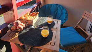 A balcony with a table set for breakfast, including croissants, peaches, and orange juice.