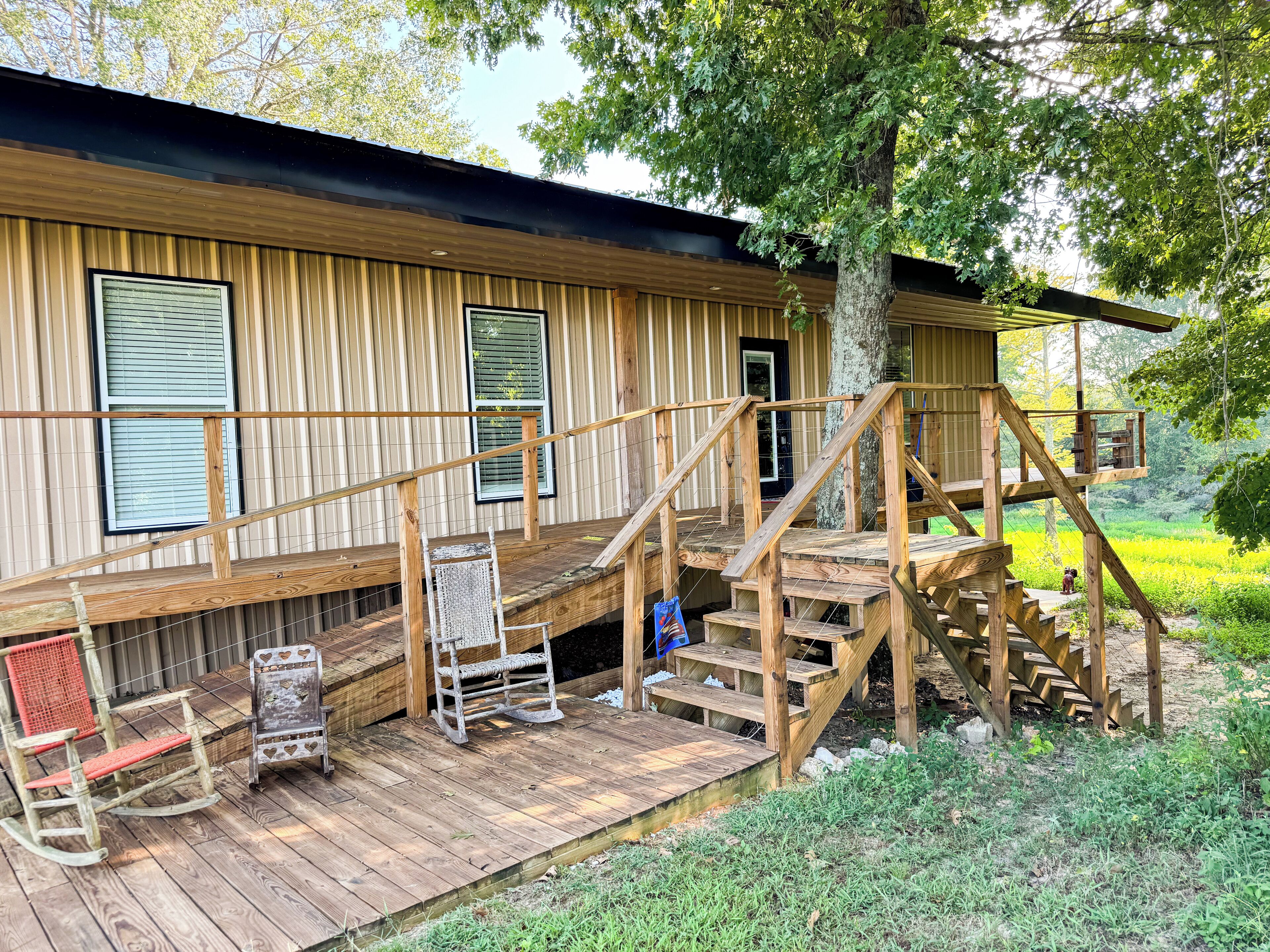 A wooden cabin with a porch, a set of wooden stairs, and a rocking chair.