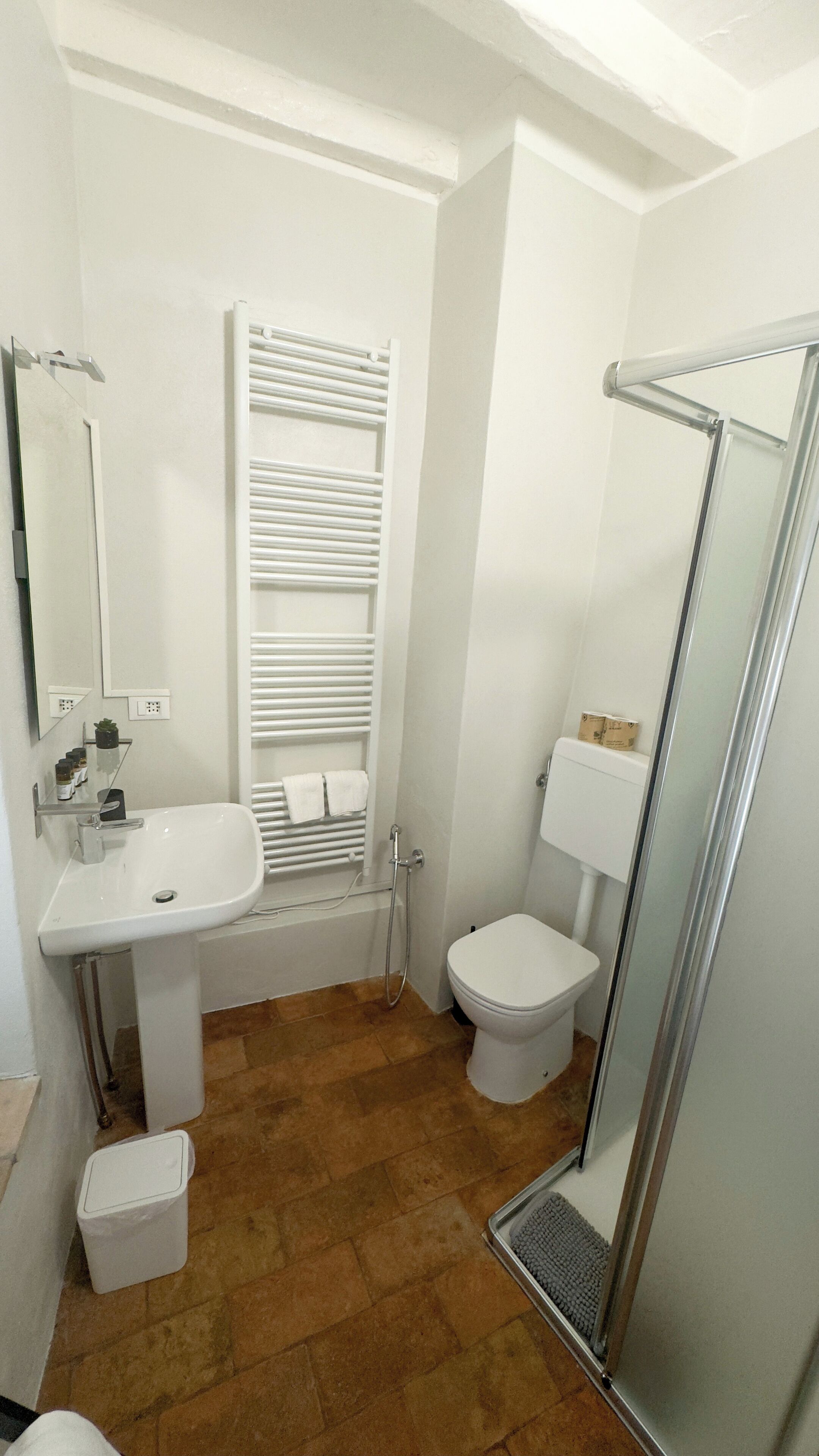 A bathroom with a white sink, toilet, and shower. There is a towel rack and a mirror above the sink.