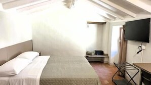 A small, cozy room with a bed, a desk, and a TV. - Residenze del borgo (Zavattarello)