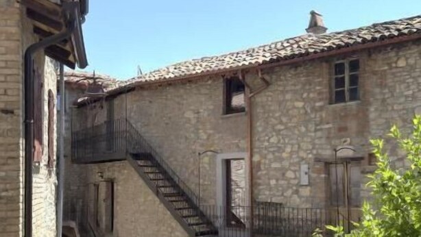 A narrow cobblestone street flanked by stone buildings with balconies and a staircase leading to an upper level. - Residenze del borgo (Zavattarello)