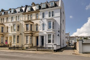 A row of white townhouses with bay windows, a blue door, and a small front garden.