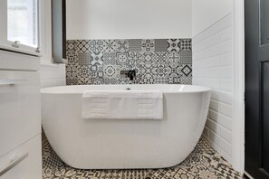Une salle de bain moderne avec une baignoire sur pieds, des carreaux décoratifs sur les murs et une fenêtre.