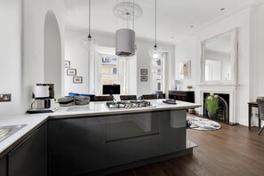 A modern kitchen with a central island, pendant lights, and a fireplace.