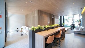 A modern reception area with a wooden reception desk, seating area, and large windows offering views of the outdoors.