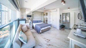 A modern bedroom with a large bed, a sofa, and a view of the city.