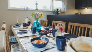 A dining table set with blue dishes, a vase with flowers, and a blue water bottle. - Skandinavisch Eingerichtetes Familienferienhaus (Sagard)