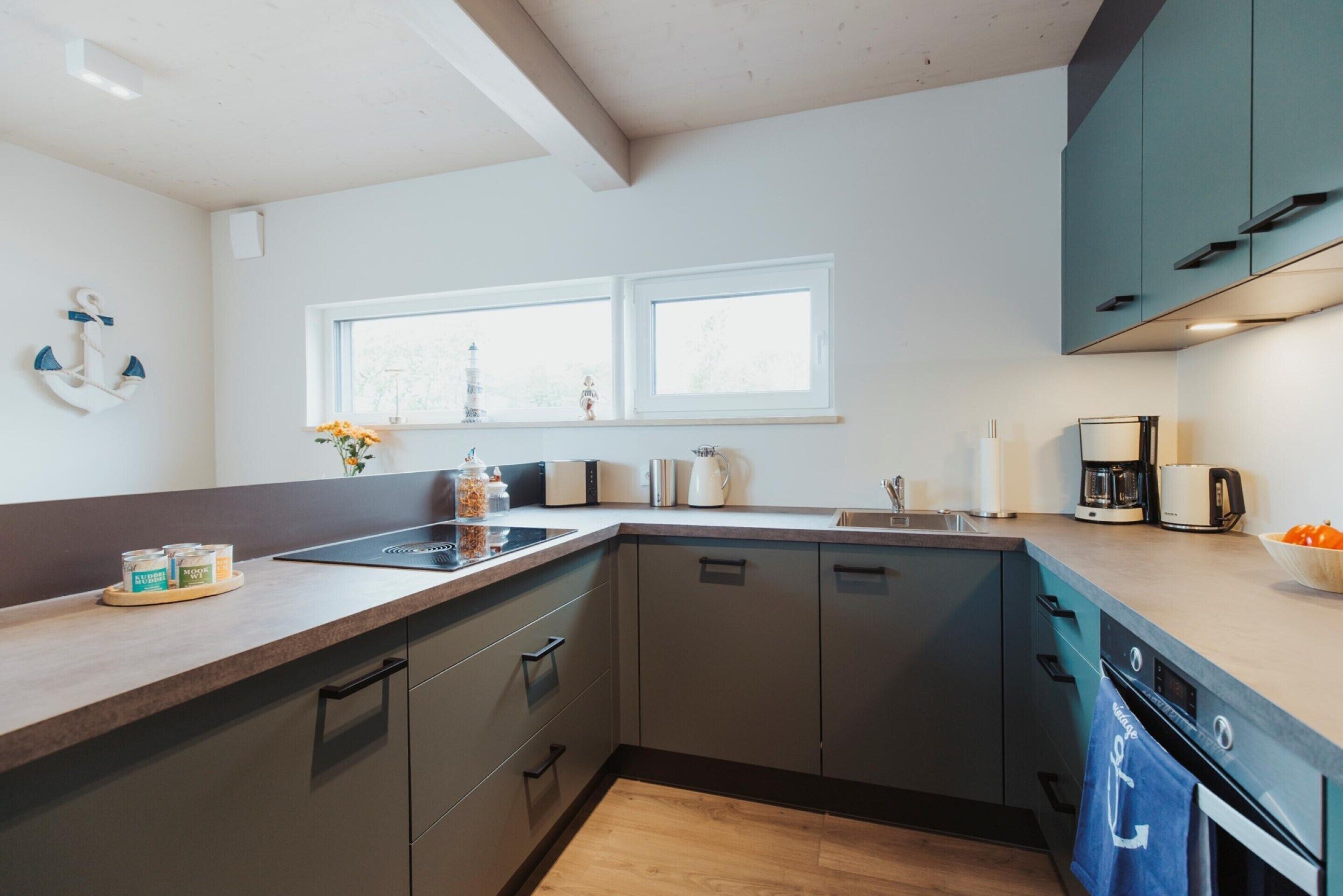 A modern kitchen with a wooden countertop, built-in cabinets, a double sink, and a window above the sink.