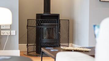A modern living room with a black wood-burning stove, a round table, and a sofa.