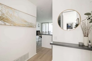 A modern interior with a kitchen area, a dining space, and a hallway leading to another room.