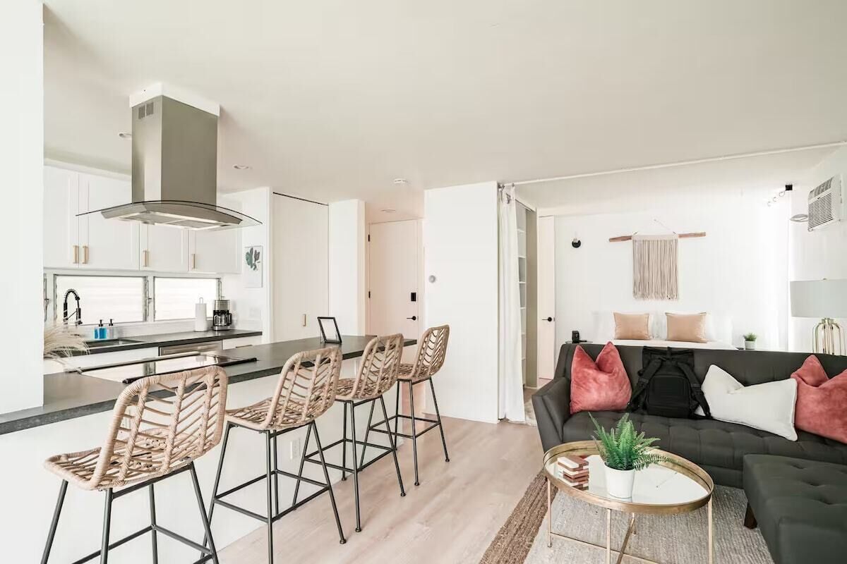 Een moderne keuken met een centraal eiland, barstoelen en een eethoek.