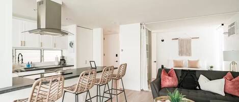 A modern kitchen with a central island, bar stools, and a dining area.