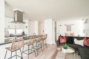 A modern kitchen with a central island, bar stools, and a dining area.