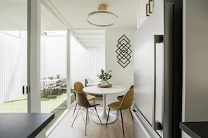 A modern kitchen with a round dining table, two chairs, and a refrigerator.