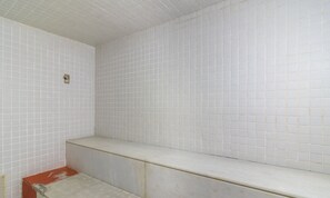 Un baño con paredes de azulejos blancos y un banco.
