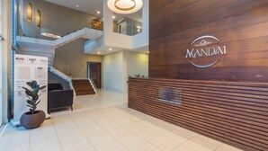 Een moderne lobby met een houten receptiebalie, een trap en een potplant.