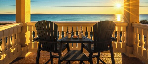 A balcony with two Adirondack chairs and a small table, overlooking a beach and ocean. - Gulf Front - Hot tub - Private Heated Pool - Views (Panama City Beach)