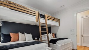 Un dormitorio con dos camas, una escalera de madera y una puerta blanca.