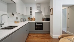 Una cocina moderna con horno empotrado, microondas y campana extractora de acero inoxidable.