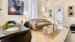 A modern living room with a sofa, coffee table, and dining area. - TREVI CHIC HOUSE CENTER OF ROME (Roma)