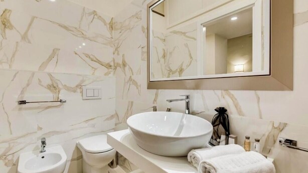 A modern bathroom with a large oval sink, a bidet, a toilet, and a mirror above the sink. - TREVI CHIC HOUSE CENTER OF ROME (Roma)