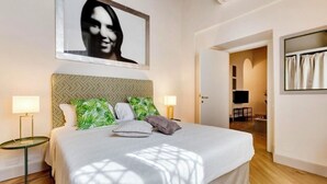 A bedroom with a bed, two bedside lamps, a headboard with a geometric pattern, and a large framed picture on the wall. - TREVI CHIC HOUSE CENTER OF ROME (Roma)