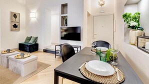 A modern living room with a dining area, a flat-screen TV, and a cozy seating arrangement. - TREVI CHIC HOUSE CENTER OF ROME (Roma)