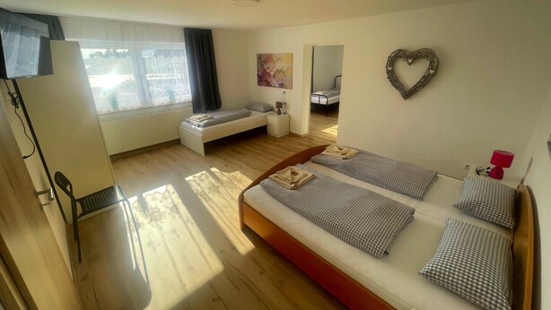 Un dormitorio moderno con una cama grande, un sofá pequeño, un escritorio y una ventana con cortinas.