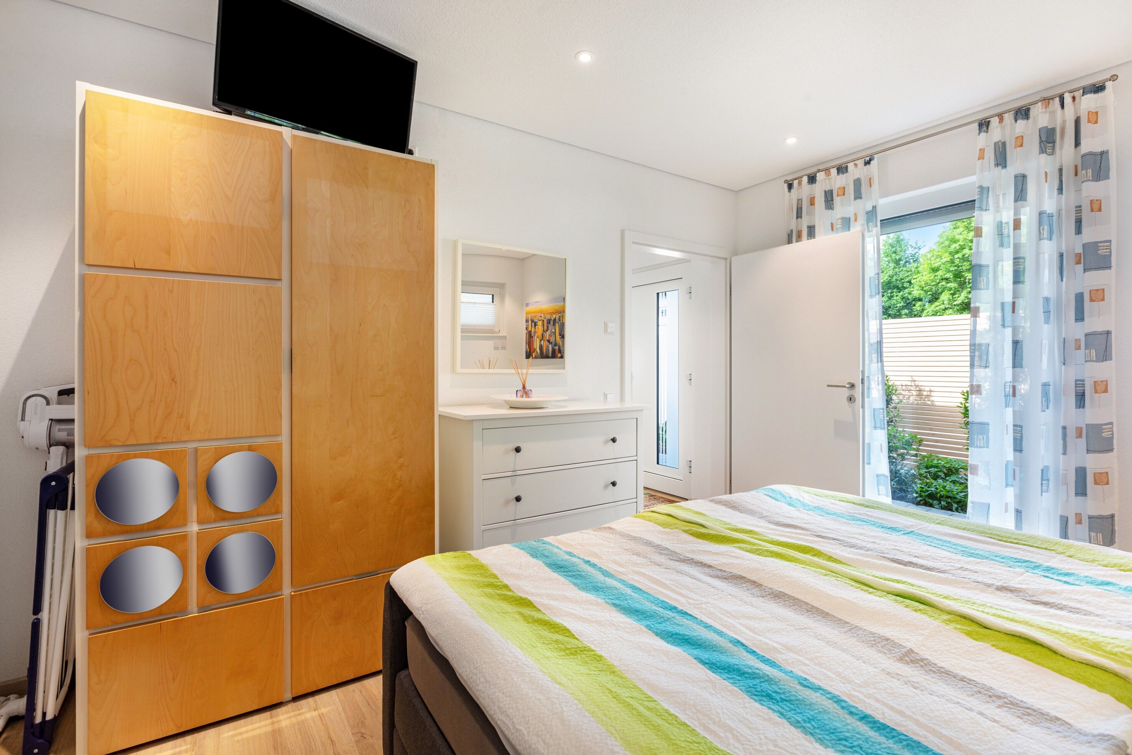 A bedroom with a bed, a wardrobe, a bathroom, and a window with curtains.