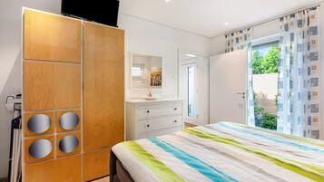 A bedroom with a bed, a wardrobe, a bathroom, and a window with curtains.