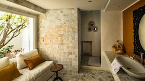 Un bagno con una parete rivestita in pietra, un lavandino bianco e uno specchio grande.