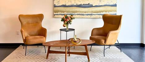 A room with two leather armchairs, a wooden coffee table, and a painting on the wall.