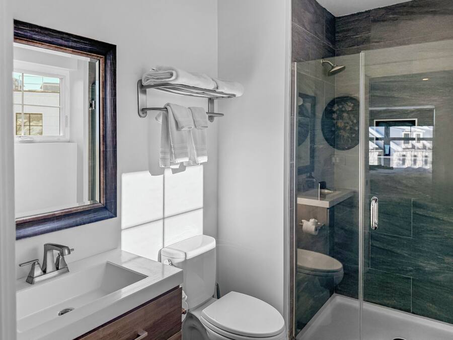 A modern bathroom with a glass-enclosed shower, a toilet, and a sink with a mirror.