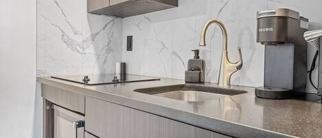 A modern kitchen with a marble backsplash, stainless steel appliances, and wooden cabinetry.