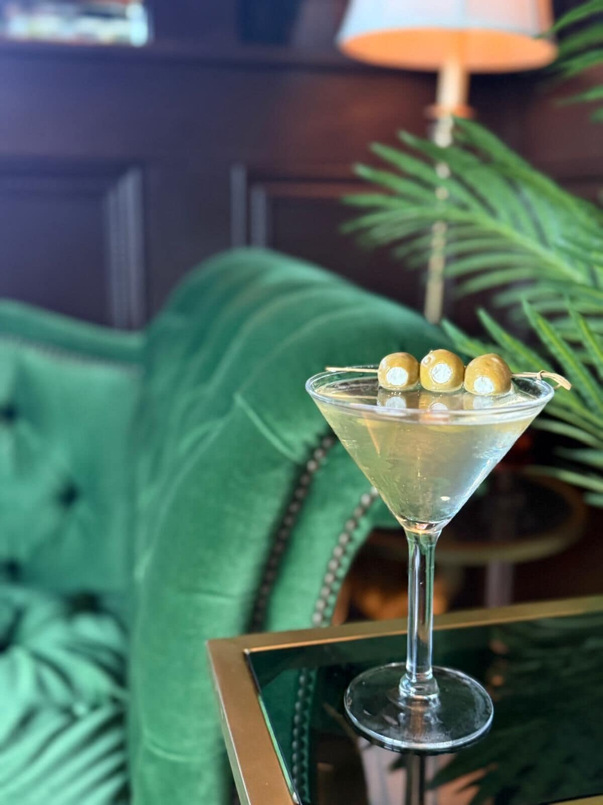 Una copa de martini con tres adornos esféricos sobre una superficie reflectante.