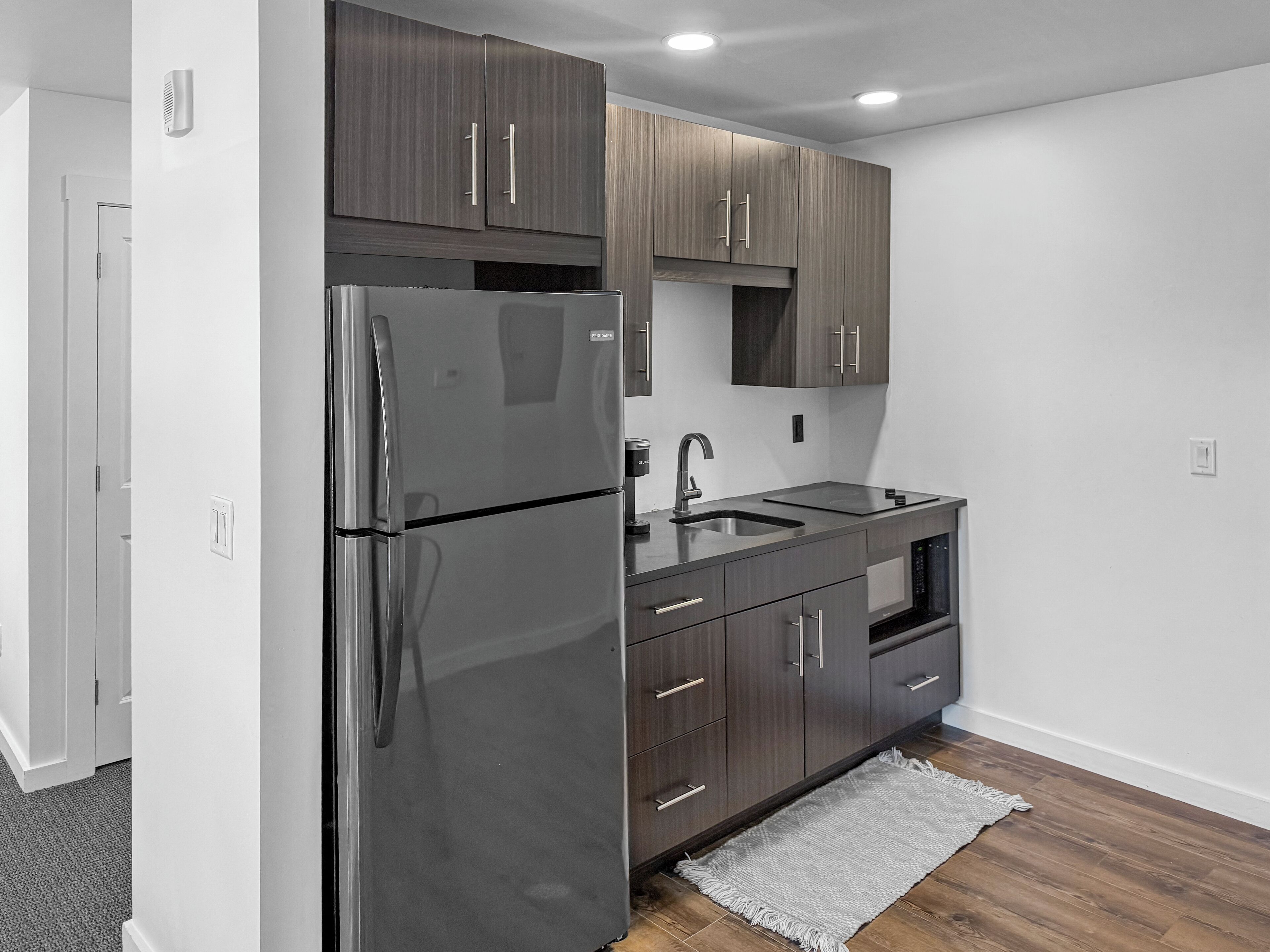 Una cocina moderna con gabinetes de madera oscura, electrodomésticos de acero inoxidable y piso de madera.